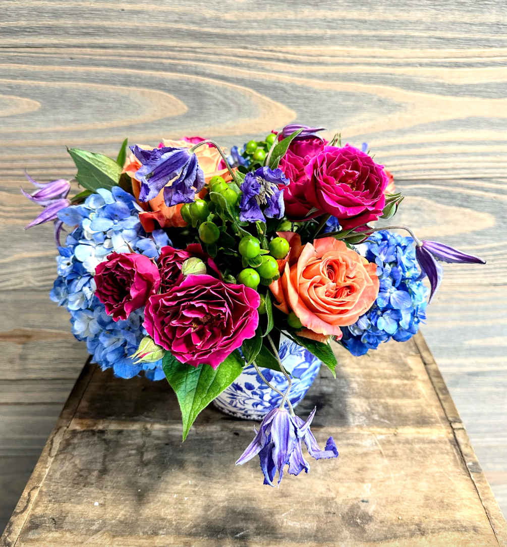 A mix of bright summer blooms in a specialty blue chinioserie pot.