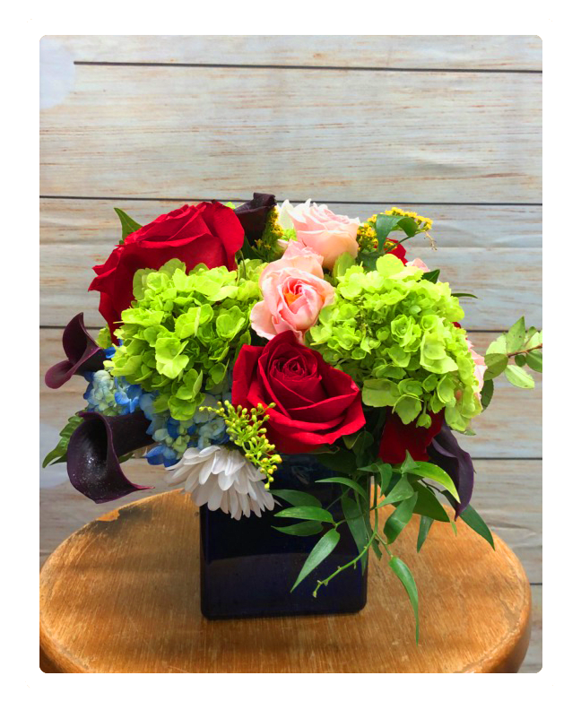 Slick cube vase arrangement made with hydrangea, roses, daisies and mini callas.