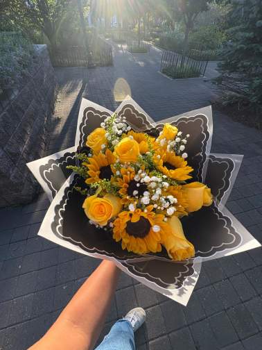 Handheld bouquet of yellow roses and sunflowers with white filler flowers