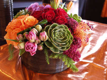 Colorful mixed flower arrangement in a round dark vase with succulents