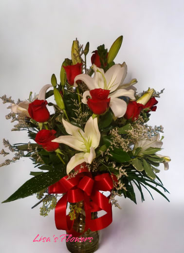 Bouquet of red roses and white lilies in a glass vase with a red ribbon