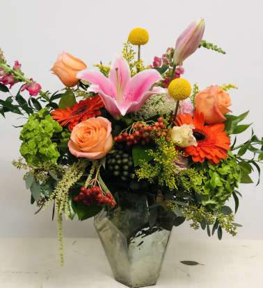 Mixed bouquet with pink lily, orange roses, and gerbera daisies in a glass vase