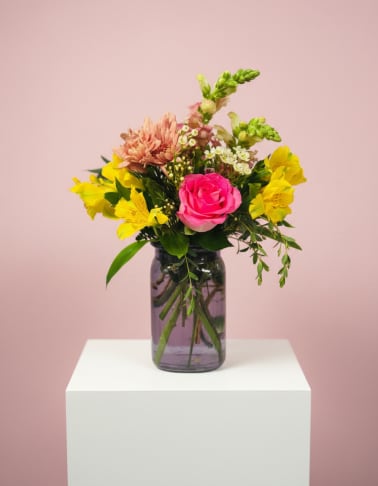 Pink rose and yellow mixed flowers in a glass vase