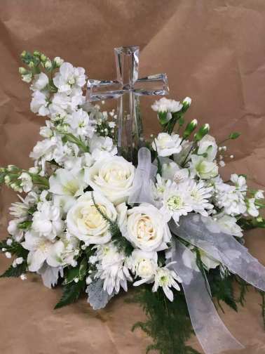 White floral arrangement with a clear cross centerpiece and sheer ribbon