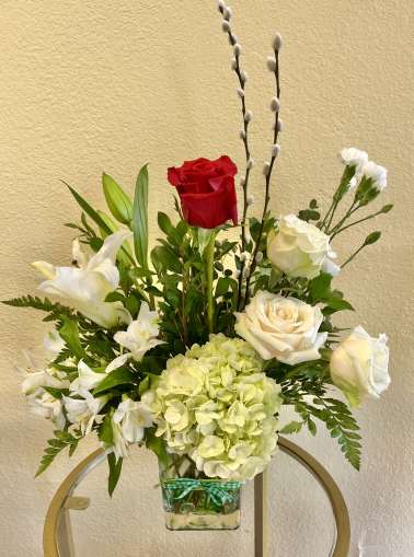 Mixed bouquet with red and white roses, lilies, and pale hydrangea in a glass vase
