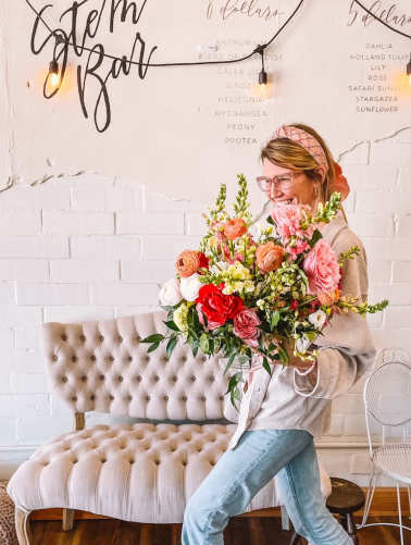 Woman holding a large mixed bouquet of pink, red, white, and peach flowers