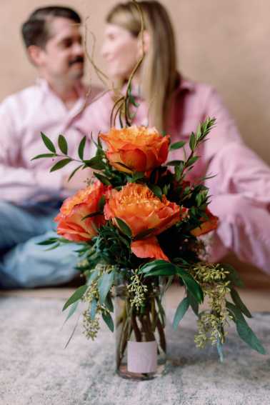 Orange roses arranged in a glass vase with greenery.