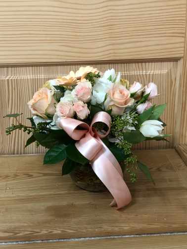Bouquet of pale pink and white flowers with a pink ribbon in a basket