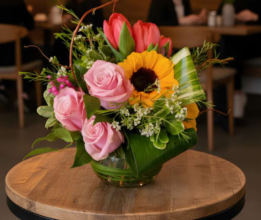 Pink roses and a sunflower arranged in a glass vase