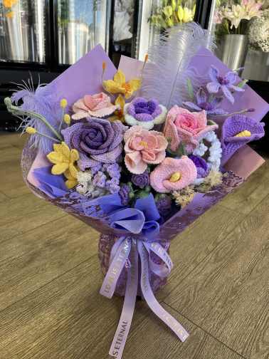 Bouquet of crocheted purple, pink, and yellow flowers wrapped in lavender paper