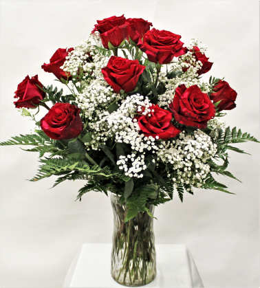 Arrangement of red roses with white filler flowers in a clear glass vase