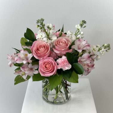 Pink roses and white flowers arranged in a clear glass vase