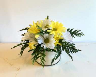 Yellow and white daisies arranged in a low white container