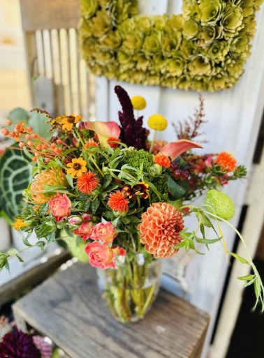 Mixed bouquet in a clear glass vase with pink, orange, and yellow blooms