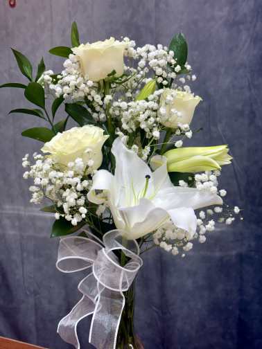 White roses and lilies arranged with baby's breath and a sheer ribbon.
