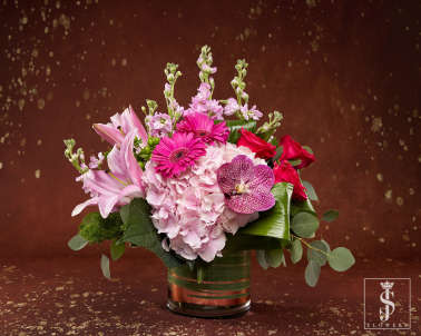 Pink and red mixed flower arrangement in a glass vase