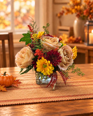 Autumn bouquet of beige roses and yellow chrysanthemums in a glass vase