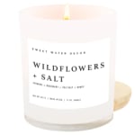 Lit white candle in a glass jar labeled Wildflowers + Salt