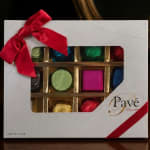 Box of assorted chocolates with a red ribbon and windowed lid