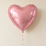 Pink heart-shaped foil balloon with a ribbon tail