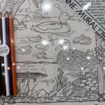 Duck and fish coloring page with three colored pencils beside it