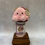 Plush pink toy sitting on a canned ham container