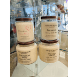 Four scented candles in glass jars stacked on a shelf
