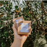 Hand holding two small brown boxes with labels in front of trees