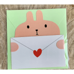 Cute bunny peeking over a white envelope with a red heart