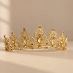 Gold jeweled tiara with clear and amber stones on a neutral background