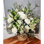 White floral arrangement in a woven basket with roses and lilies