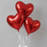 Three red heart-shaped balloons tied with white ribbons