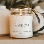 A lit candle in a clear glass jar with a white label
