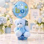 Blue teddy bear with a baby boy balloon and flowers in the background