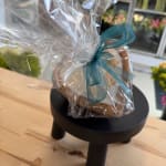 Wrapped gift basket with a teal ribbon on a small black stand