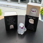 Small ghost figurines in black gift boxes on a table