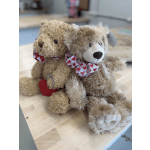 Two plush teddy bears with heart-patterned bows sitting together