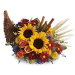 Sunflowers and mixed blooms arranged with wheat and cinnamon sticks in a wicker cornucopia