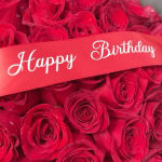 Red roses with a red ribbon reading Happy Birthday