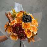Bouquet of orange roses and burgundy mums with dried leaves