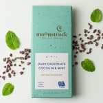 Mint chocolate bar in a teal box with cocoa nibs and mint leaves