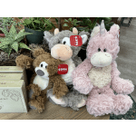 Three plush unicorn toys sit beside potted plants.