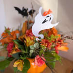 Halloween floral arrangement in an orange pumpkin container with a ghost topper