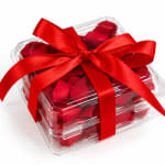Clear gift box filled with red rose petals and tied with a red ribbon