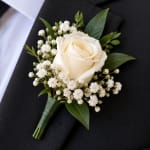 White rose boutonniere with baby's breath on a dark suit jacket