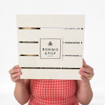 Person holding a wooden crate with a Bonnie & Pop label