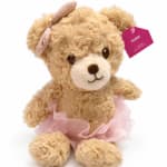 Plush teddy bear with a pink ribbon and tag