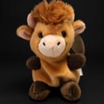 Plush giraffe toy with a fluffy mane on a black background