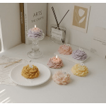 Flower-shaped candles in pastel colors arranged on a white tabletop