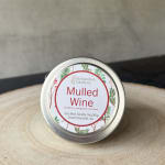 Tin candle labeled Mulled Wine on a wooden surface